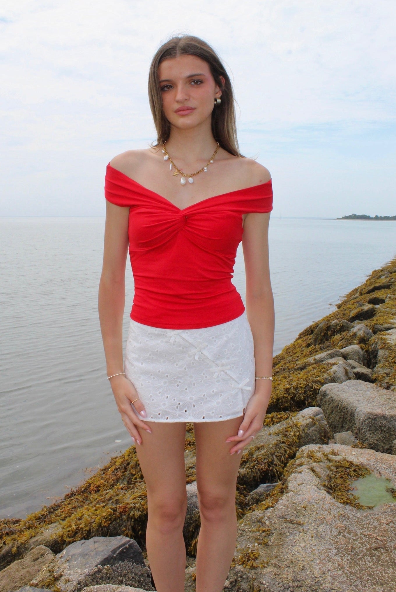 Woman wearing a red off the shoulder top and white eyelet skirt. Fourth of July Outfit Inspo