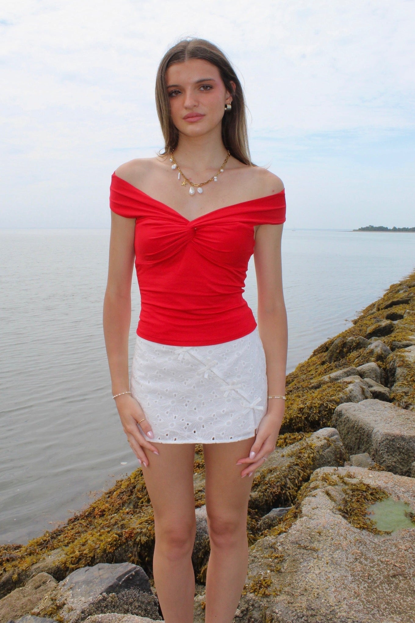 Woman wearing a red off the shoulder top and white eyelet skirt. Fourth of July Outfit Inspo