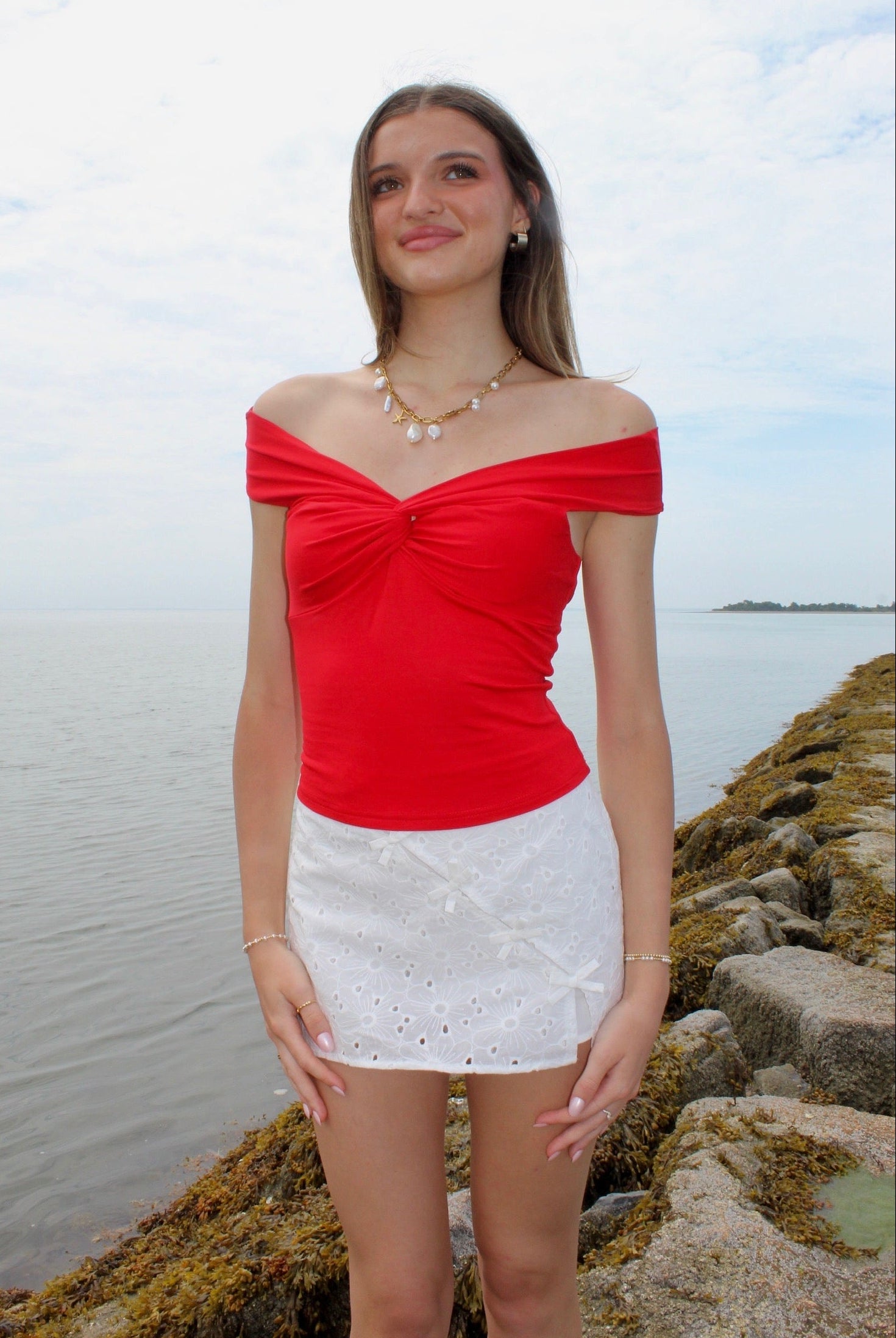 Woman wearing a red off the shoulder top and white eyelet skirt. Fourth of July Outfit Inspo