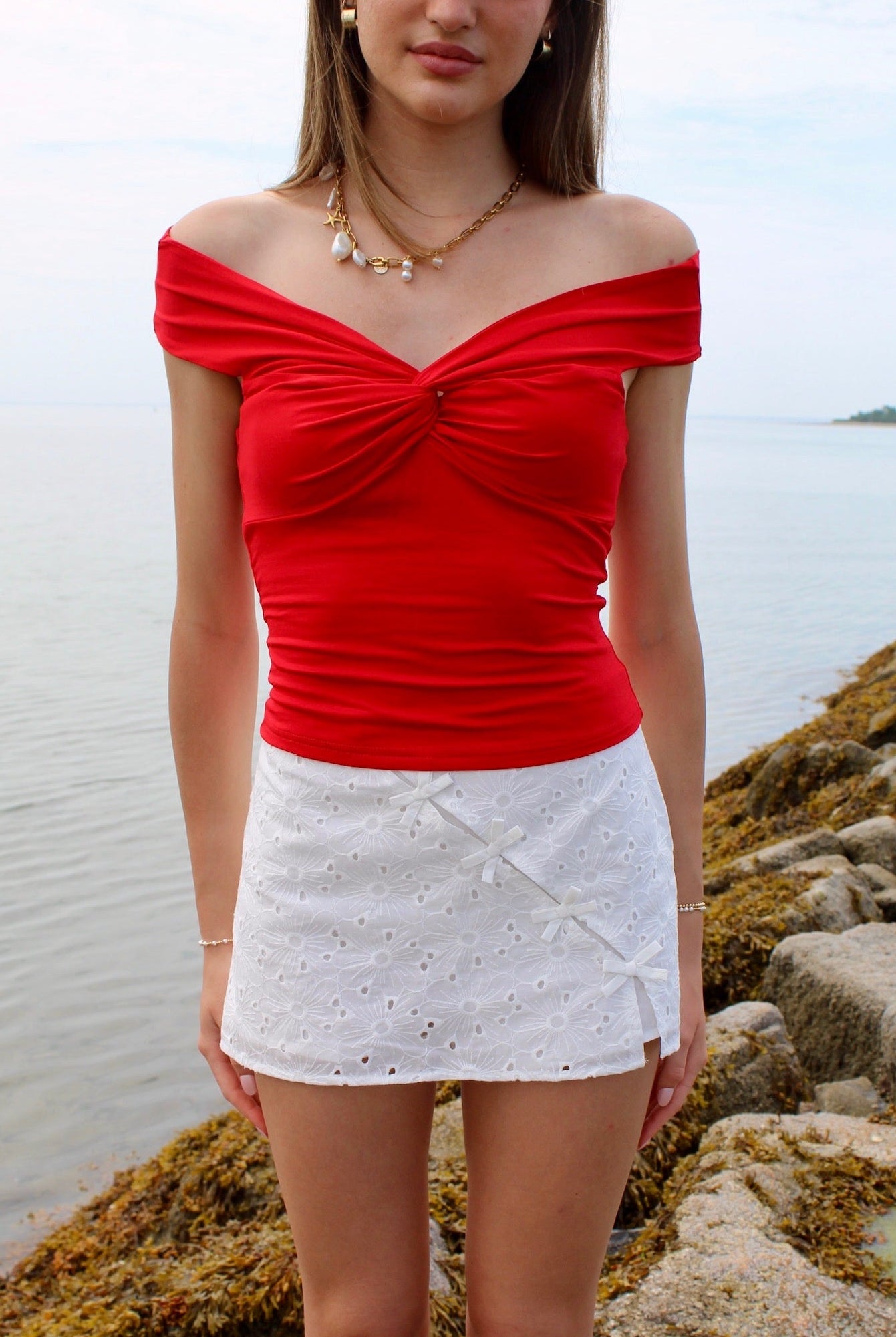 Woman wearing a red off the shoulder top and white eyelet skirt. Fourth of July Outfit Inspo