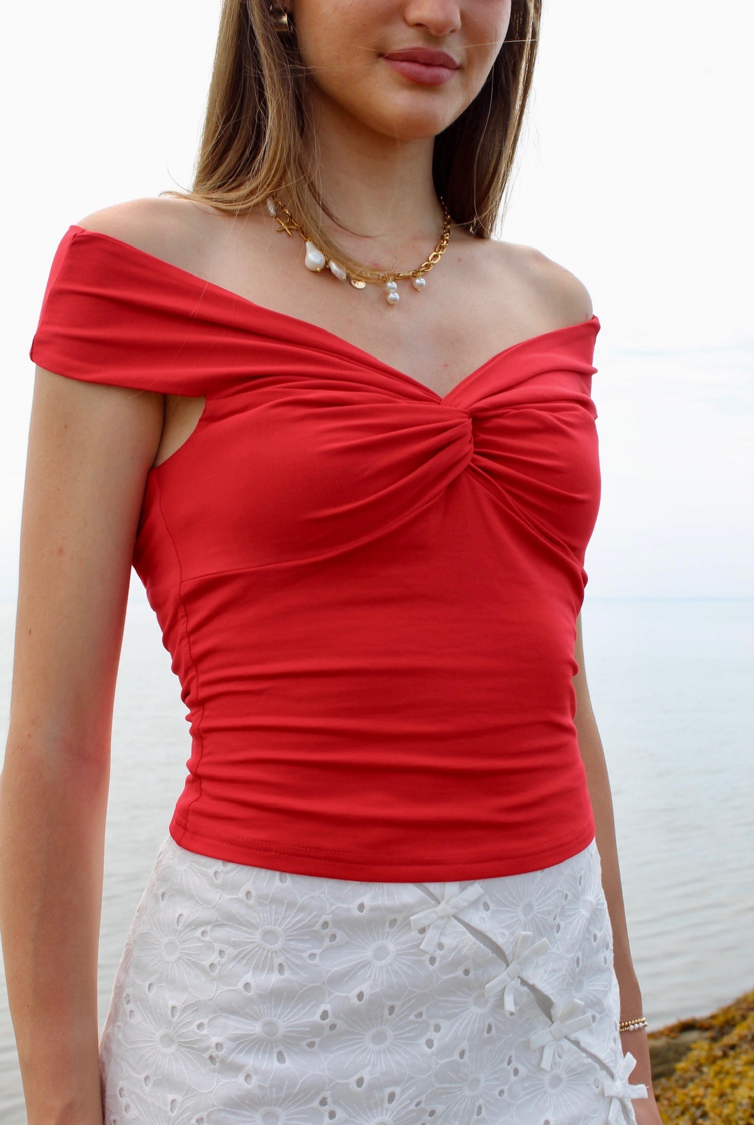 Woman wearing a red off the shoulder top and white eyelet skirt. Fourth of July Outfit Inspo