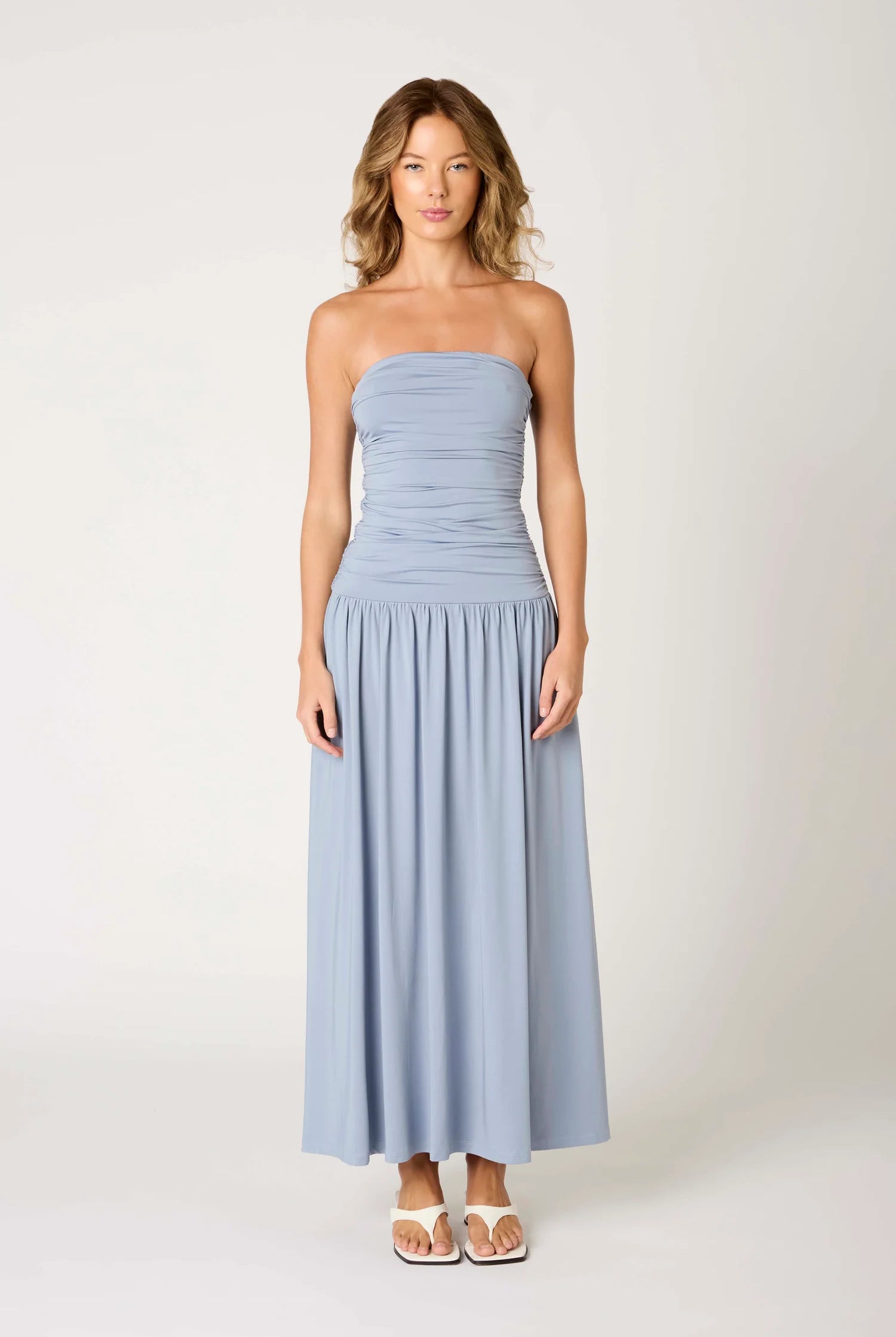 Woman wearing a light blue strapless dress on a white background
