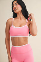 Woman wearing a double layered pink sports bra and leggings against a neutral background