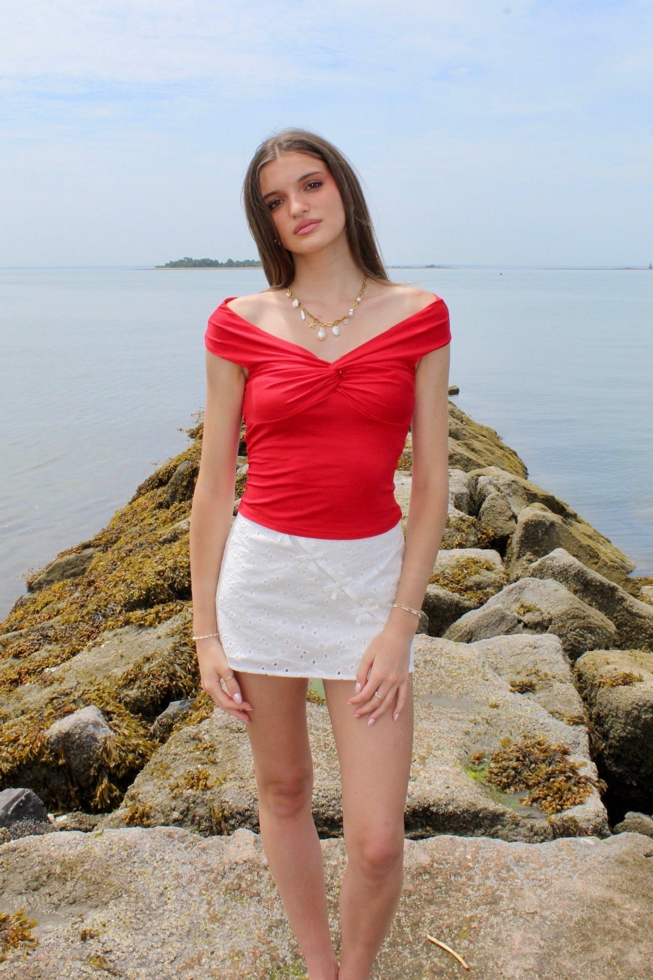 Woman wearing a red off the shoulder top and white eyelet skirt. Fourth of July Outfit Inspo