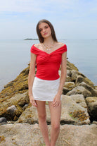 Woman wearing a red off the shoulder top and white eyelet skirt. Fourth of July Outfit Inspo