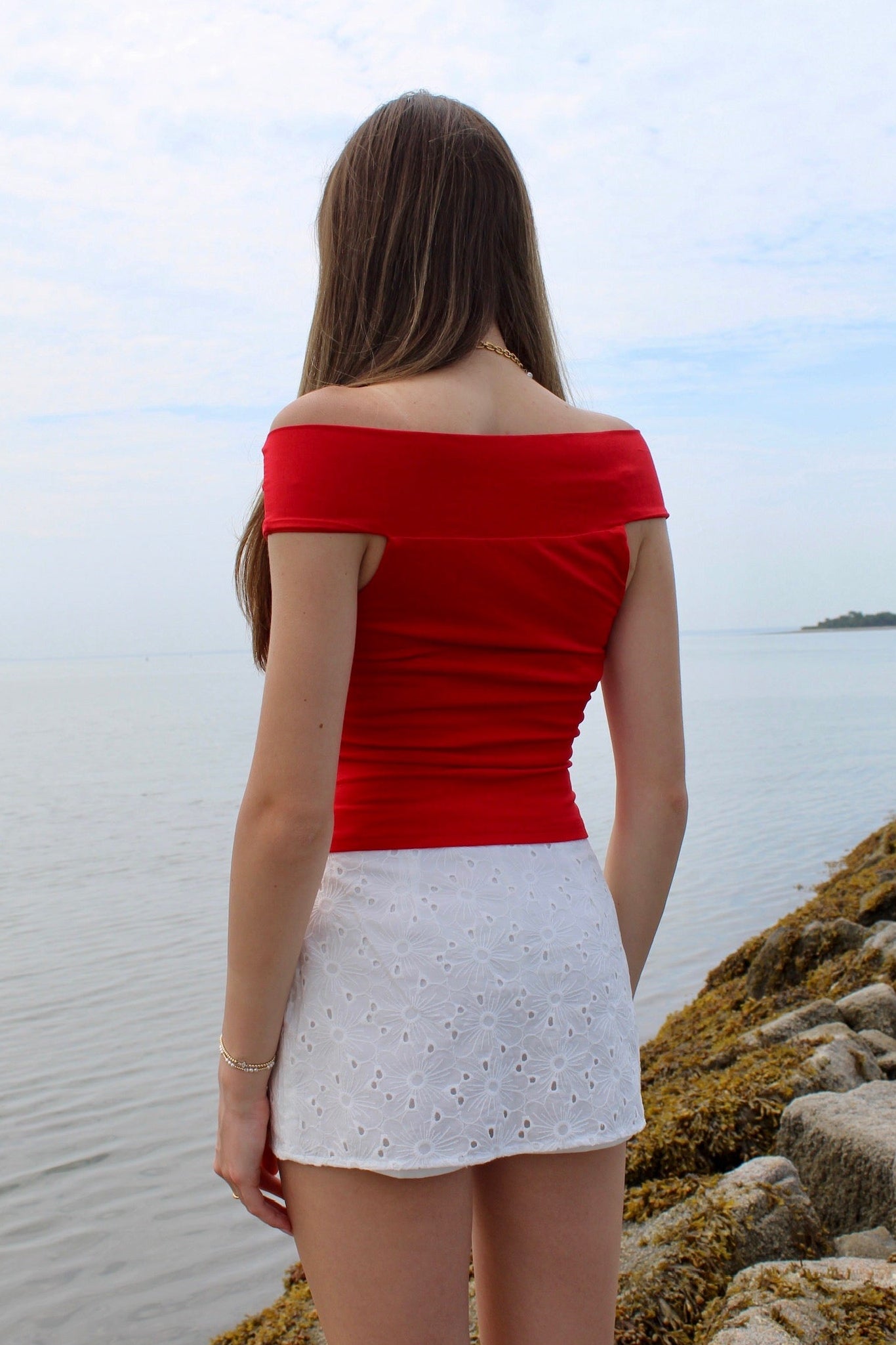 Woman wearing a red off the shoulder top and white eyelet skirt. Fourth of July Outfit Inspo