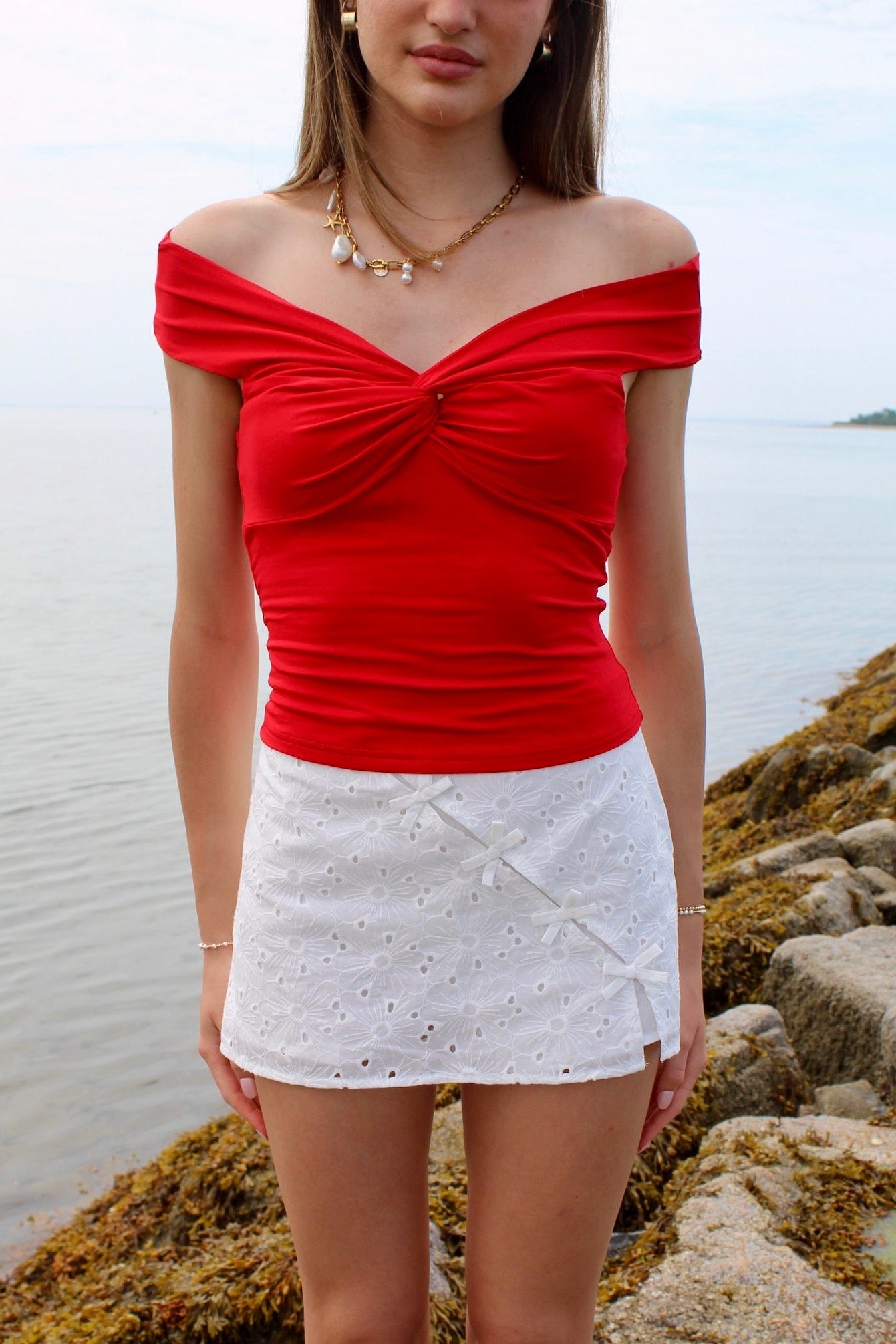 Woman wearing a red off the shoulder top and white eyelet skirt. Fourth of July Outfit Inspo