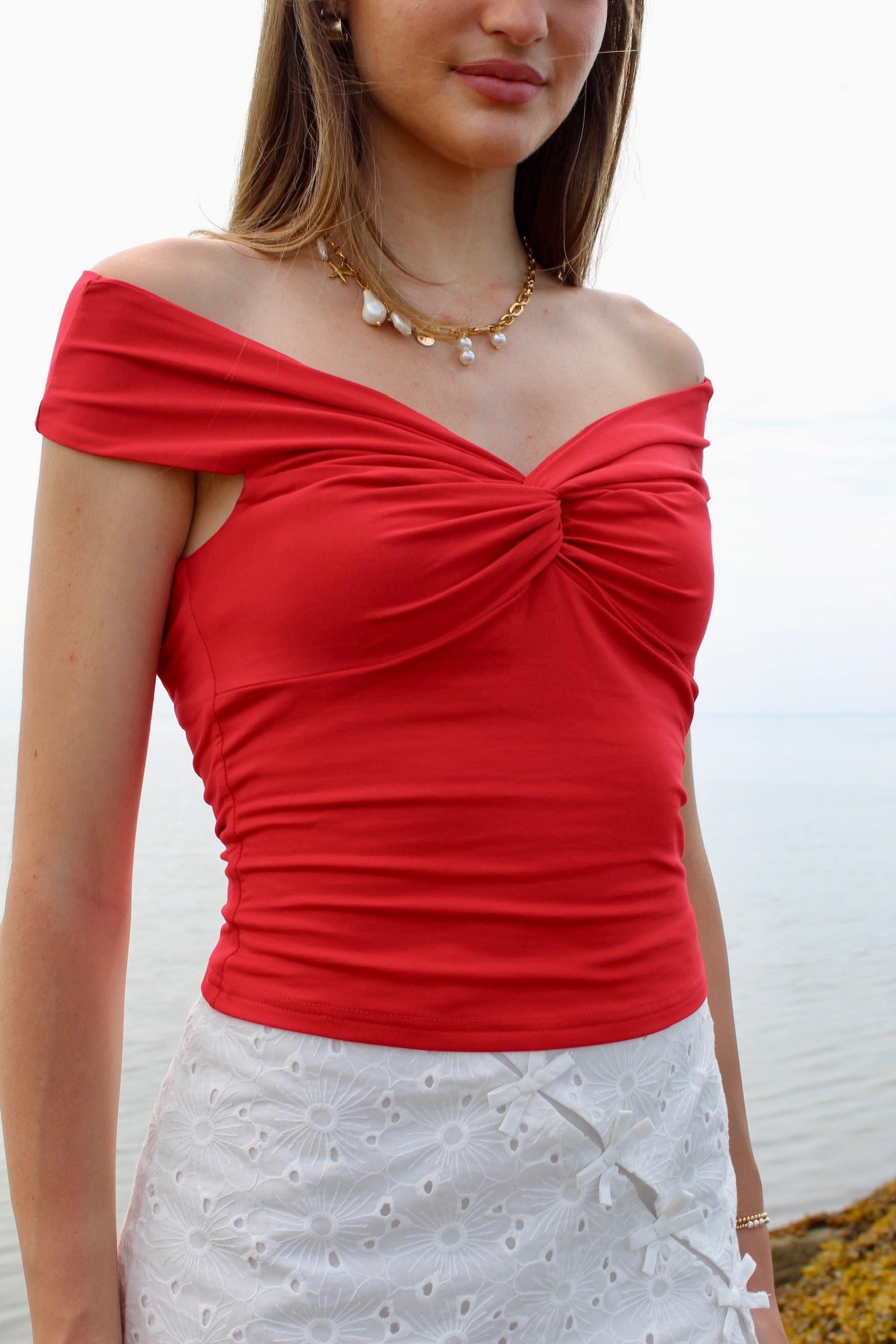 Woman wearing a red off the shoulder top and white eyelet skirt. Fourth of July Outfit Inspo