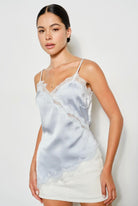 Woman wearing a light blue satin camisole with lace trim against a white background. Perfect going out top!