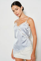 Woman wearing a light blue satin camisole with lace trim against a white background. Perfect going out top!