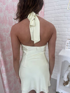 Back view of a stylish yellow halter dress with a bow tie detail, perfect for summer occasions.