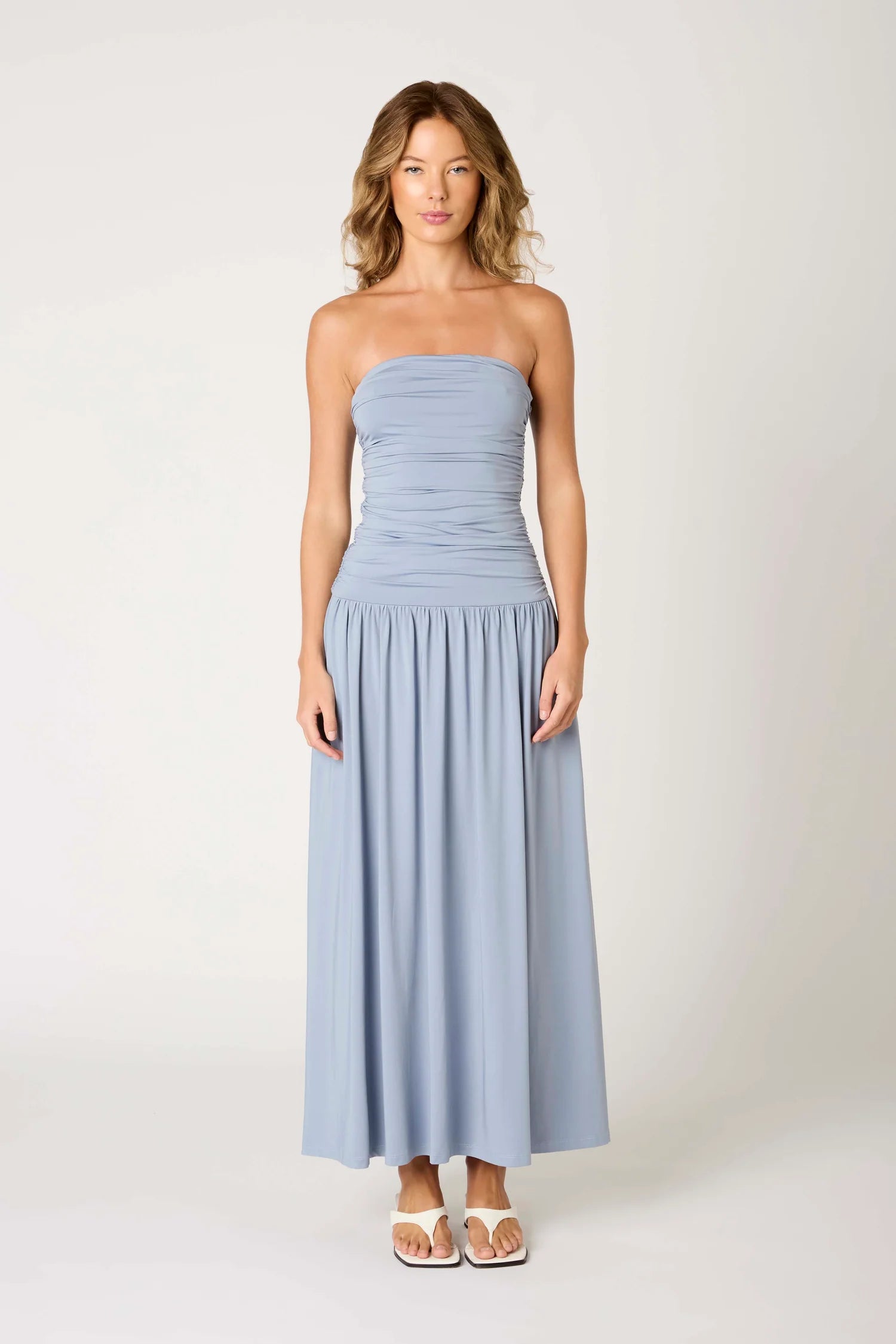 Woman wearing a light blue strapless dress on a white background
