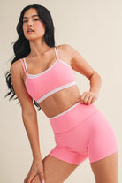 Woman wearing a double layered pink sports bra and leggings against a neutral background. cute athletic set